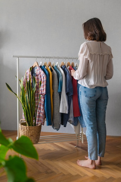 Une femme européenne à la maison dans une armoire sélectionne des vêtements pour une fête ou une fête d'anniversaire triant les vêtements