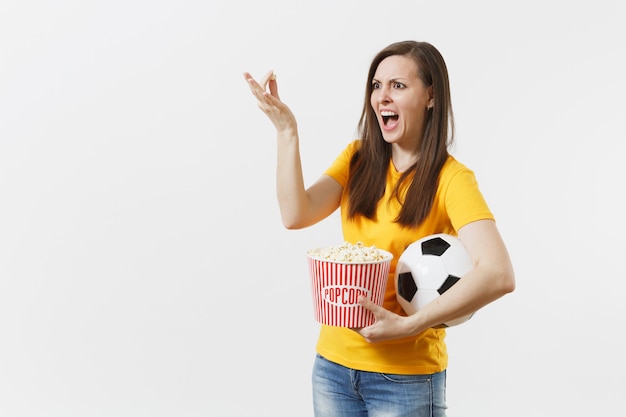 Femme européenne qui crie, fan de football tenant un ballon de football, seau de pop-corn bouleversé par la perte ou le but de l'équipe favorite isolée sur fond blanc. Sport, jouer au football, encourager, concept de mode de vie des fans.