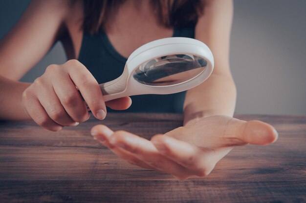 Femme examinant ses ongles avec une loupe