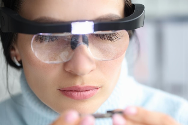 Une femme examine quelque chose portant des loupes avec éclairage