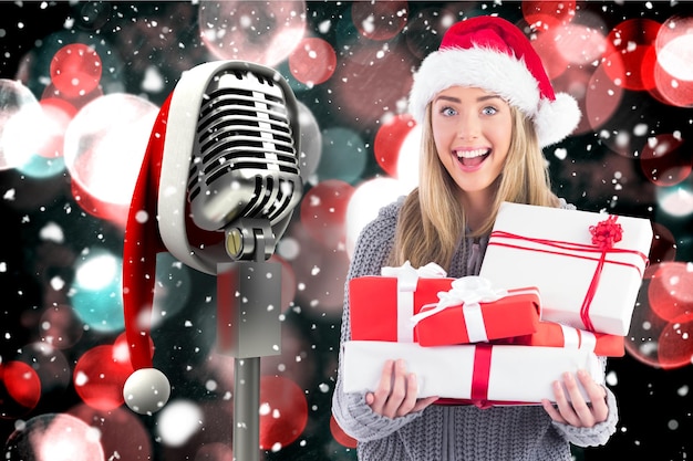 Femme excitée en bonnet de noel tenant une pile de cadeaux