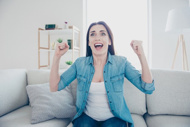 Femme excitée à la maison sur le canapé