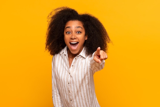 Une femme excitée pointant vers l'avant sur un fond jaune