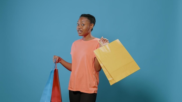 Femme excitée présentant des sacs à provisions avec des vêtements après avoir acheté en vente dans un magasin de détail. Une personne accro du shopping se sentant heureuse après avoir effectué un paiement avec de l'argent, montrant l'achat à la caméra.