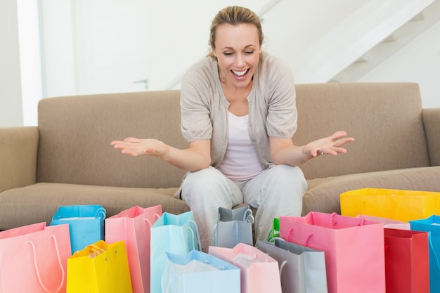 Femme excitée en regardant de nombreux sacs à provisions