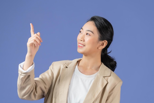 Femme excitée souriante montrant une publicité pointant le doigt vers le haut debout sur fond violet