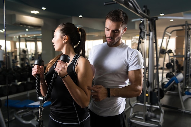 Femme exerçant des biceps avec son entraîneur personnel