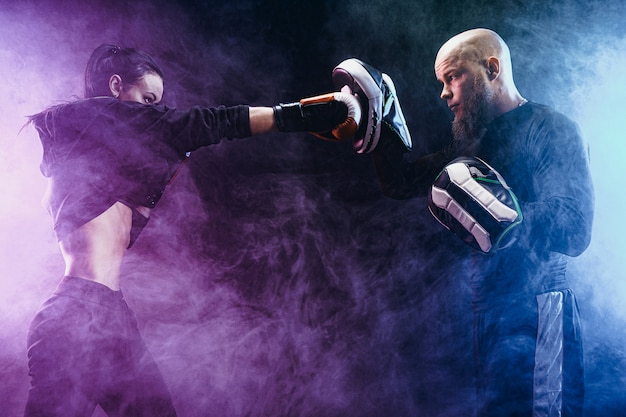 Photo femme exerçant avec entraîneur à la leçon de boxe et d'autodéfense