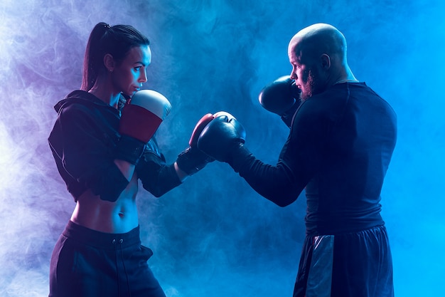 Femme exerçant avec entraîneur à la leçon de boxe et d'autodéfense