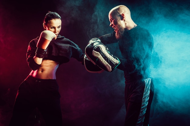 Photo femme exerçant avec entraîneur à la leçon de boxe et d'autodéfense