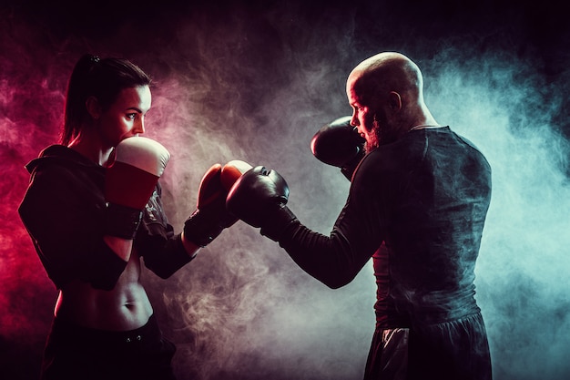 Femme exerçant avec entraîneur à la leçon de boxe et d'autodéfense