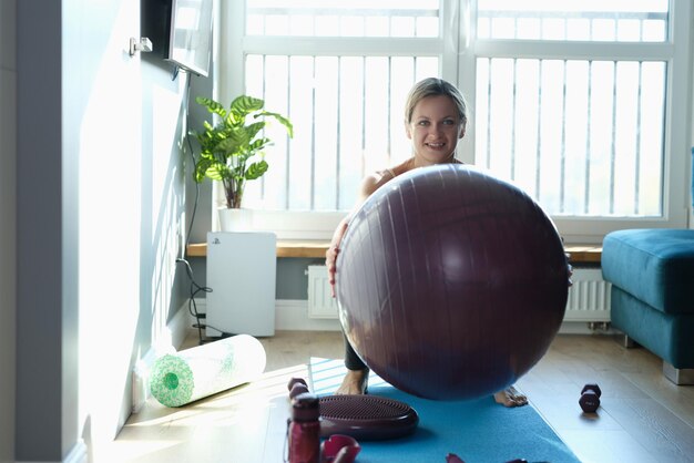 Femme exerçant et faisant des squats avec ballon à la maison