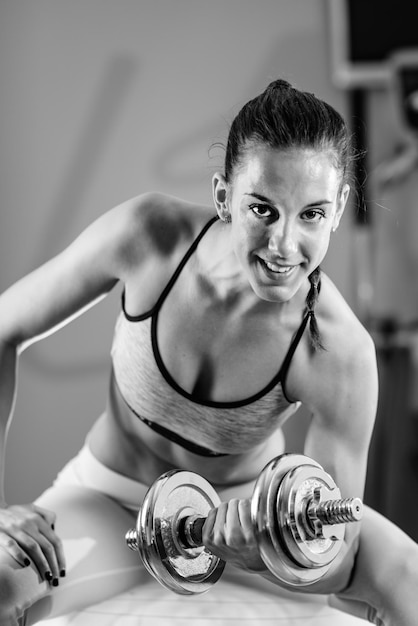 Femme exerçant avec des poids dans la salle de gym