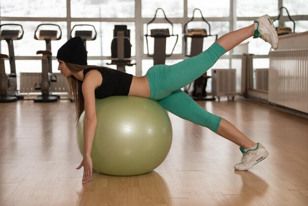 Femme exerçant une posture d'entraînement de balle Pilates dans un club de remise en forme