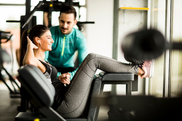 Femme exercice dans une salle de sport avec l&#39;aide de son entraîneur personnel