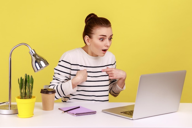 Femme avec une expression choquée regardant l'écran d'un ordinateur portable avec la bouche ouverte parlant lors d'un appel vidéo