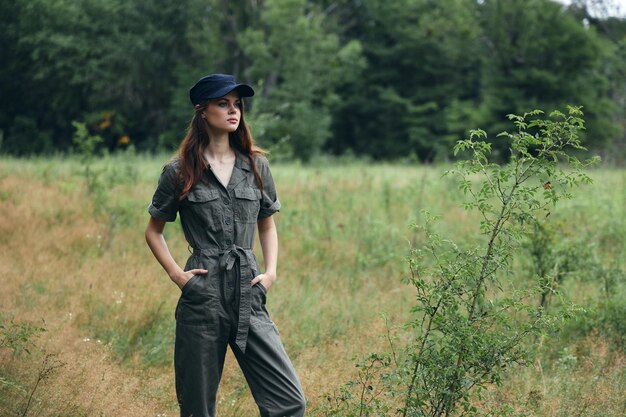 Femme à l'extérieur en combinaison grise tient les mains dans les poches et une casquette sur la tête Photo de haute qualité