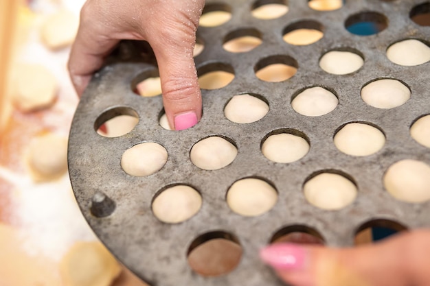 une femme extrait des boulettes crues de l'appareil pour faire des boulettes maison