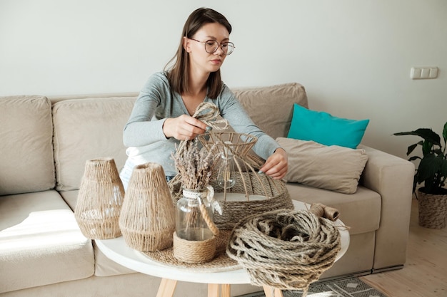 Une femme fabrique une lampe de bricolage faite à la main à partir d'une corde de jute à la maison