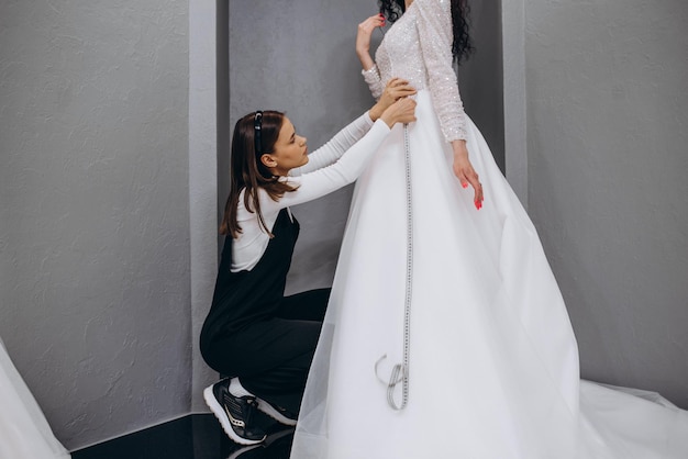 Femme faisant des ajustements à la robe de mariée dans un studio de créateurs de mode