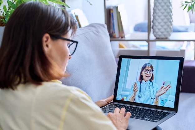 Femme faisant un appel vidéo avec un médecin en ligne se rencontrer à la maison