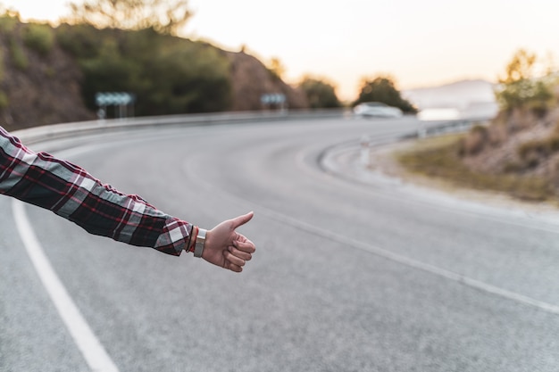 Femme faisant de l'auto-stop sur la route en attendant une voiture. Concept d'exploration et d'aventures.