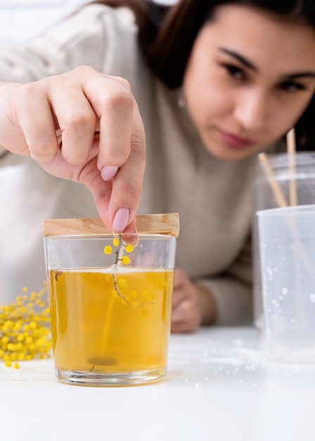 Femme faisant une bougie décorative à table avec un gros plan de mimosa