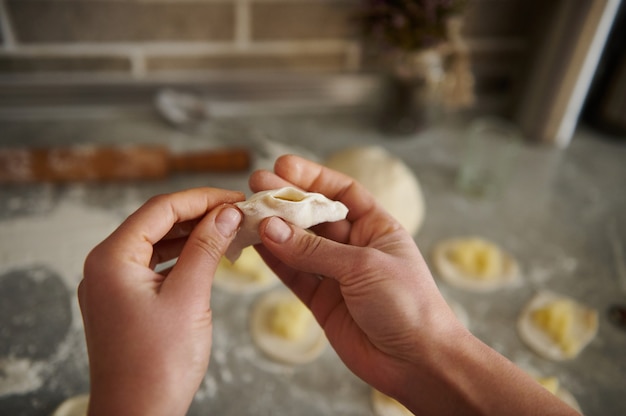 Une femme faisant des boulettes traditionnelles (vareniki ou ravioli). Focus sur les mains