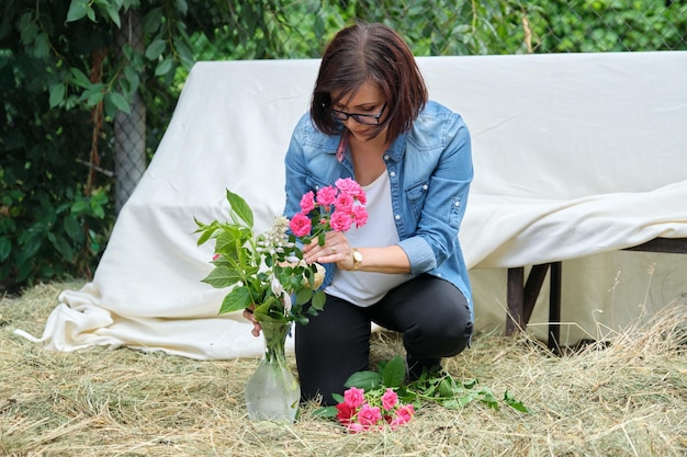 Femme faisant un bouquet de fleurs dans un vase en plein air