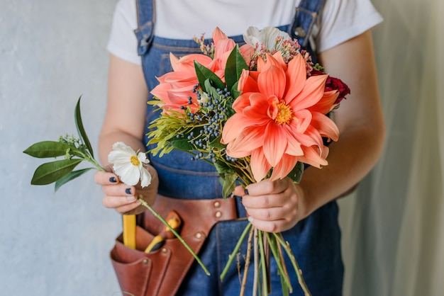 Femme faisant un bouquet de pivoines fraîches du jardin. Création d'un bouquet printanier avec des fleurs rouges et orange.