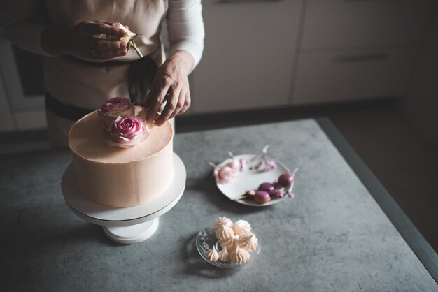 Photo femme faisant la décoration de gâteaux avec des roses de fleurs