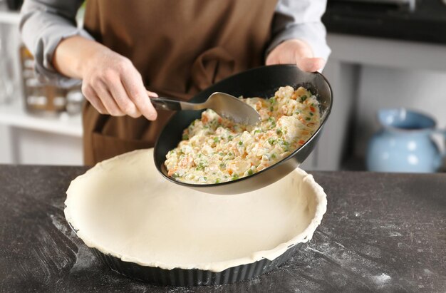 Femme faisant une délicieuse tarte au poulet sur la table de la cuisine