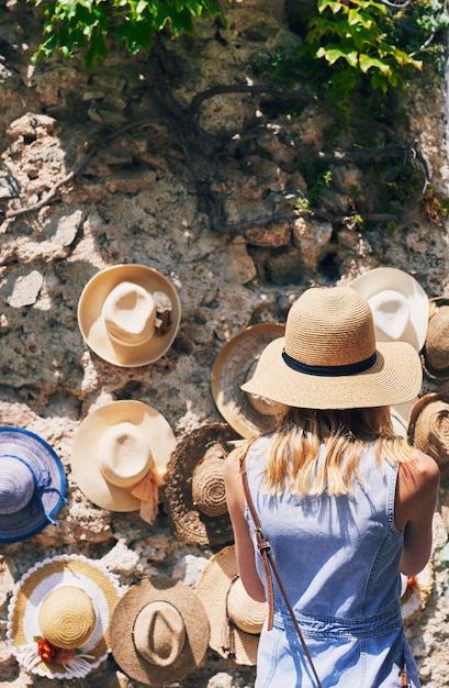 Femme faisant du shopping pour des chapeaux en Italie pendant les vacances d'été. Vue arrière d'une femme explorant la ville d'Italie. Femme faisant du shopping pour des chapeaux en Italie pendant les vacances d'été. Vue arrière d'une femme explorant la ville d'Italie.