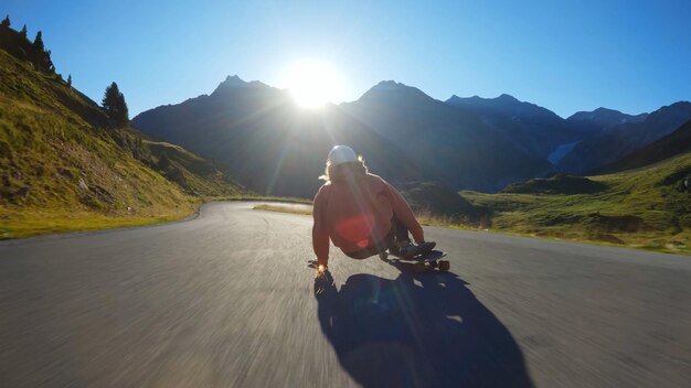 Femme faisant du skateboard et faisant des tours entre les courbes sur un col de montagne