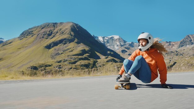 Femme faisant du skateboard et faisant des tours entre les courbes sur un col de montagne