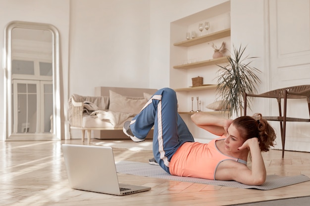 Femme faisant du sport devant un ordinateur portable à la maison