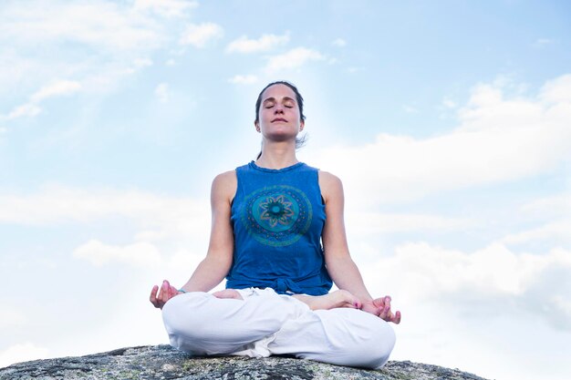 Femme faisant du yoga assis sur un rocher