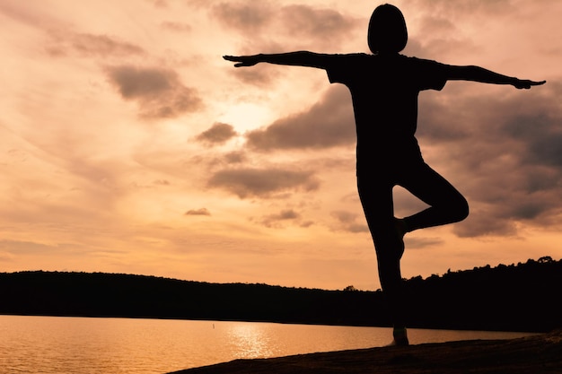Une femme faisant du yoga au coucher du soleil.