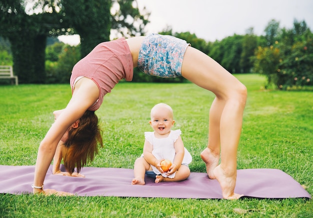 Femme faisant du yoga avec bébé dans un parc d'été Famille à l'extérieur Parent avec enfant passe du temps ensemble