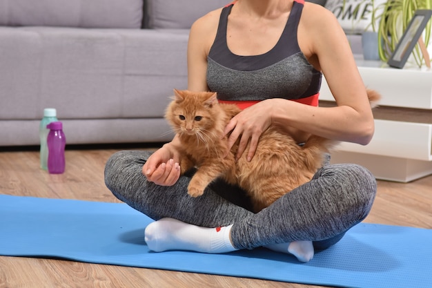 Femme faisant du yoga avec chat rouge