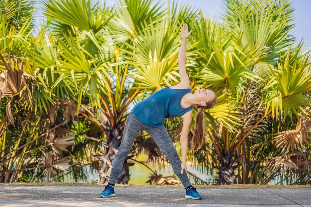 Femme faisant du yoga dans un parc tropical