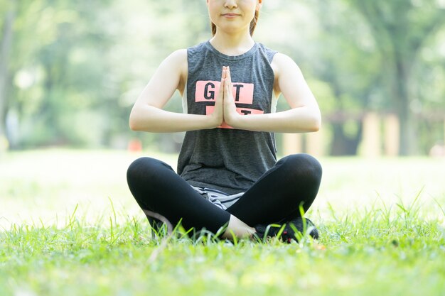 Femme faisant du yoga dans le parc