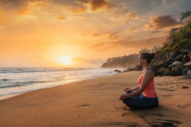 Femme faisant du yoga à la plage - Padmasana lotus pose