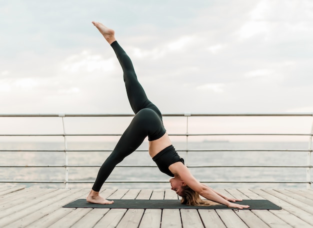 Femme faisant du yoga sur la plage en position d'asana difficile