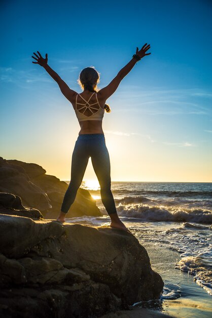 Femme faisant du yoga sur la plage