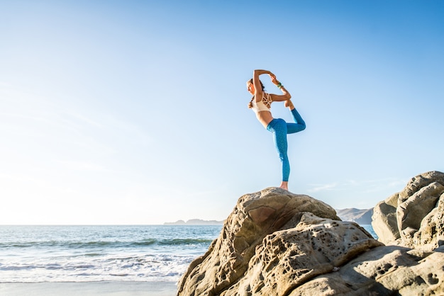 Femme faisant du yoga sur la plage