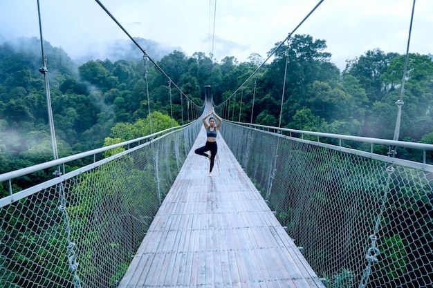 Une femme faisant du yoga sur le pont suspendu