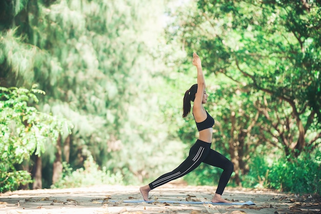 Femme faisant du yoga sur le sentier contre les arbres