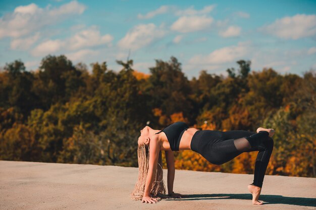 Femme faisant du yoga sur le toit d'un gratte-ciel dans la grande ville.