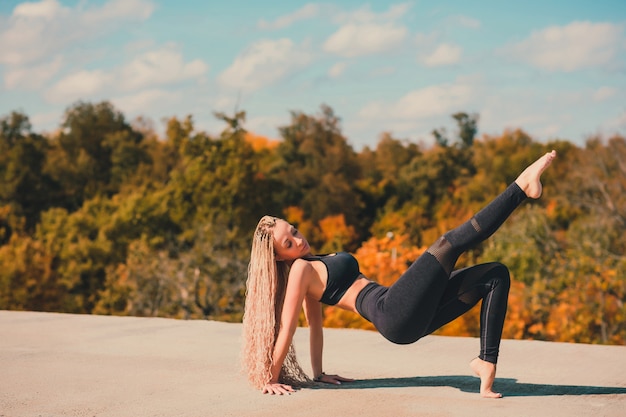 Femme faisant du yoga sur le toit d'un gratte-ciel dans la grande ville.